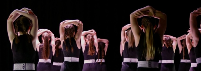 student dancers on stage with arms above their heads